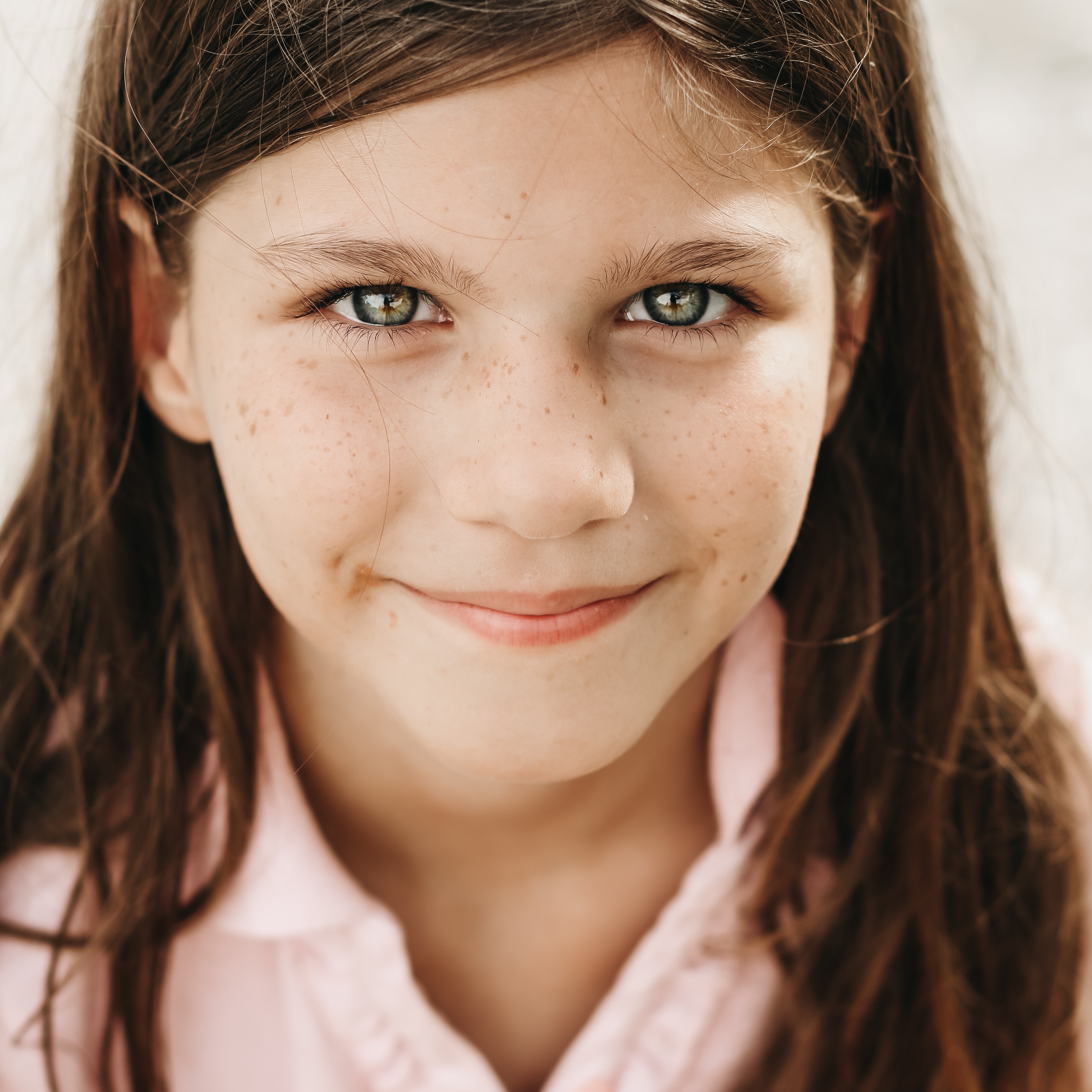 Young Girl smiling while wearing a light pink polo shirt