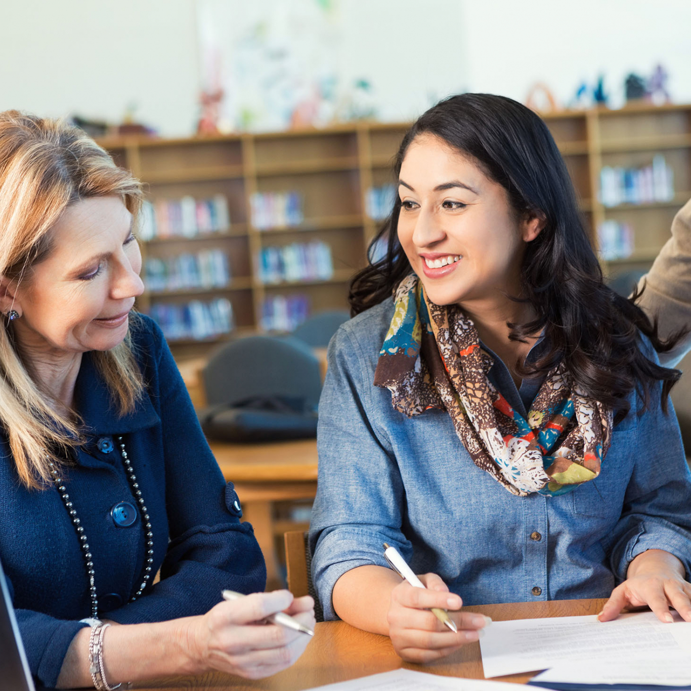 Adult college student talking to professor or classmate in library
